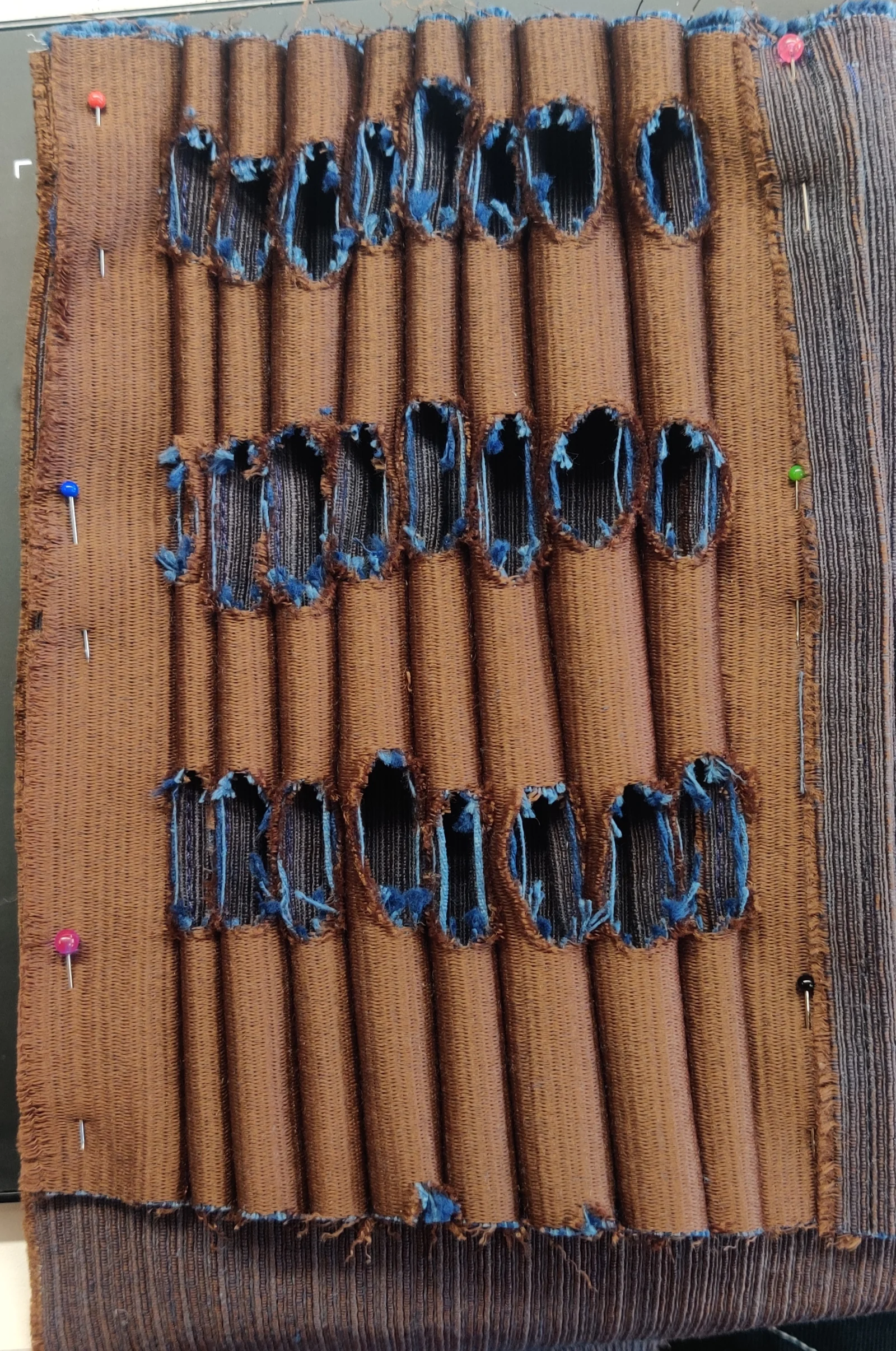 The Elon Musk Fit's double-sided fabric manipulation, oval cut-outs revealing the blue underlayer, pinned in progress